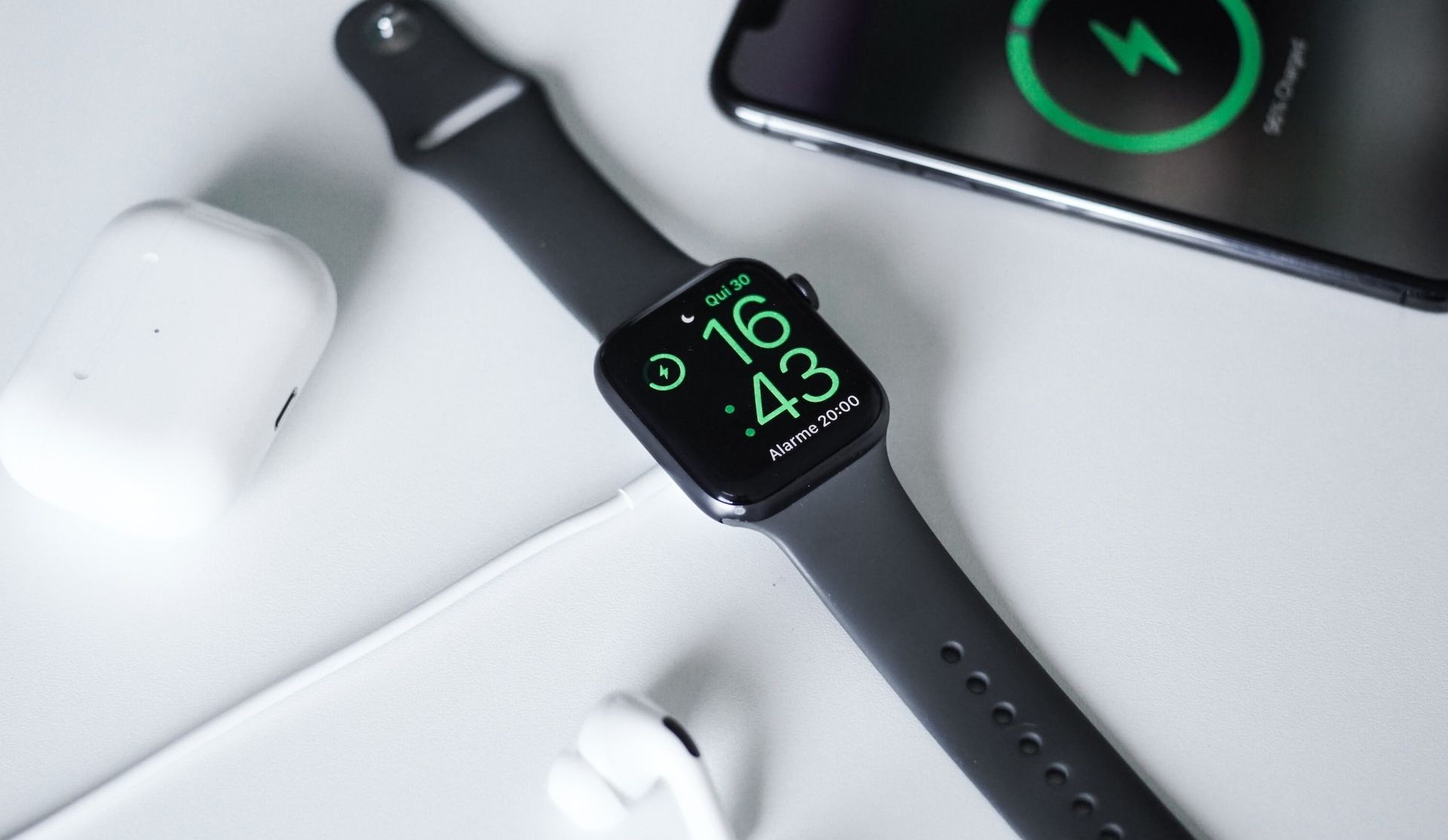 Apple Watch đang sạc trên bàn cạnh AirPods và iPhone