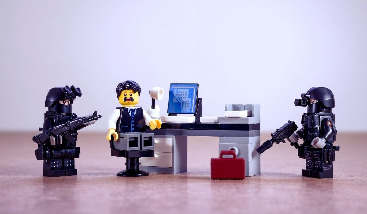 Cảnh sát Lego bao vây một người Lego ngồi tại bàn làm việc
