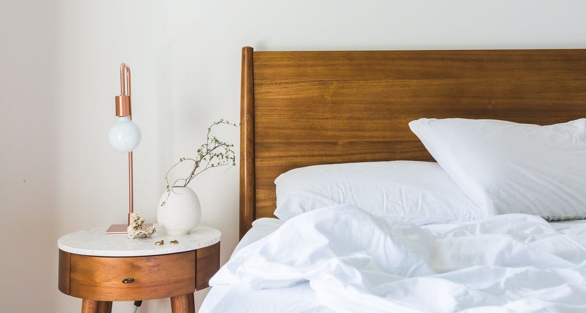Giường gỗ trắng với đèn bàn đầu giường bằng đồng