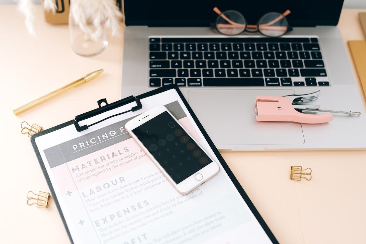 Hình ảnh iPhone và giấy tờ bên cạnh máy tính xách tay