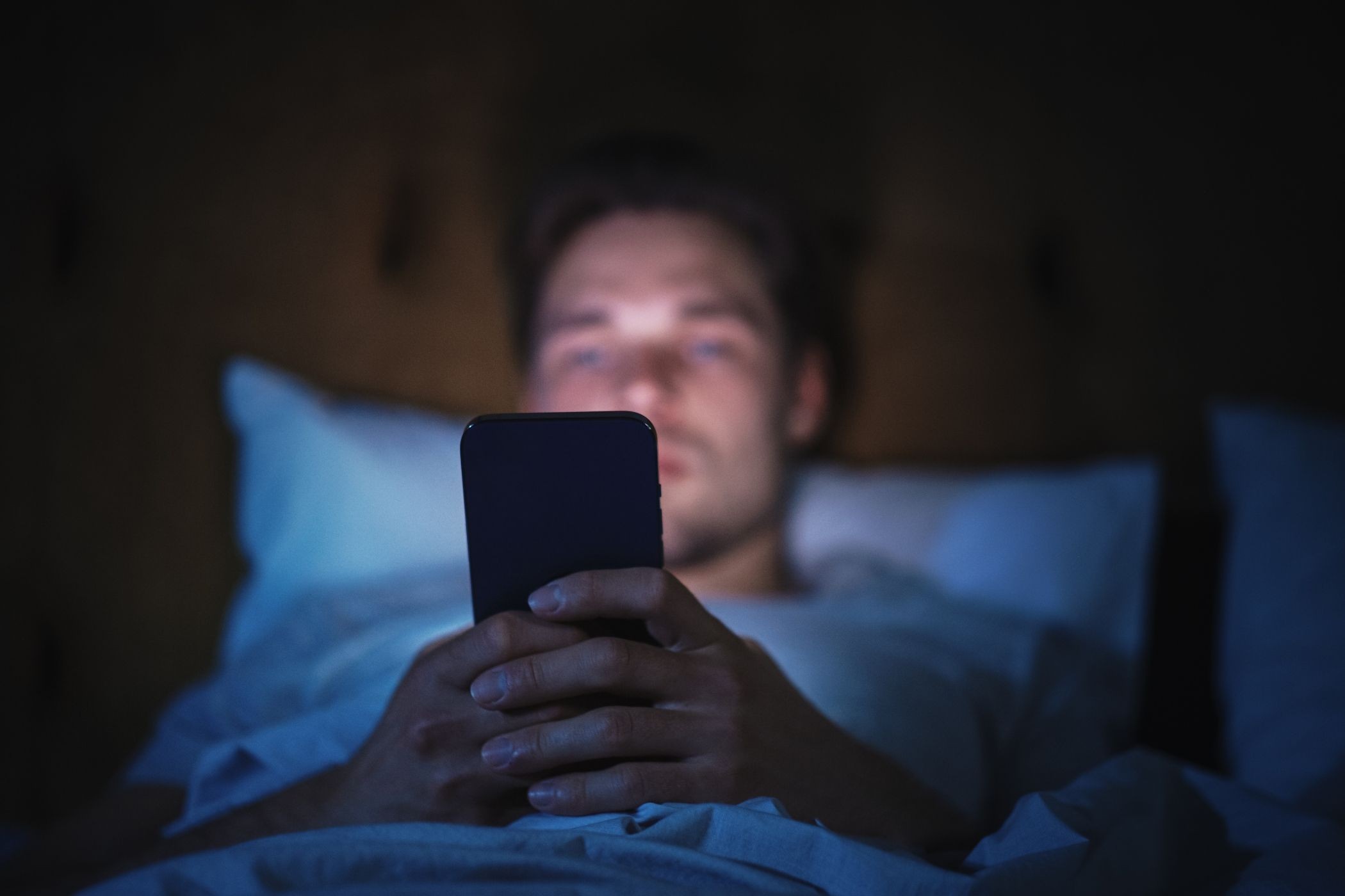 Hình ảnh người đàn ông sử dụng smartphone khi nằm trên giường