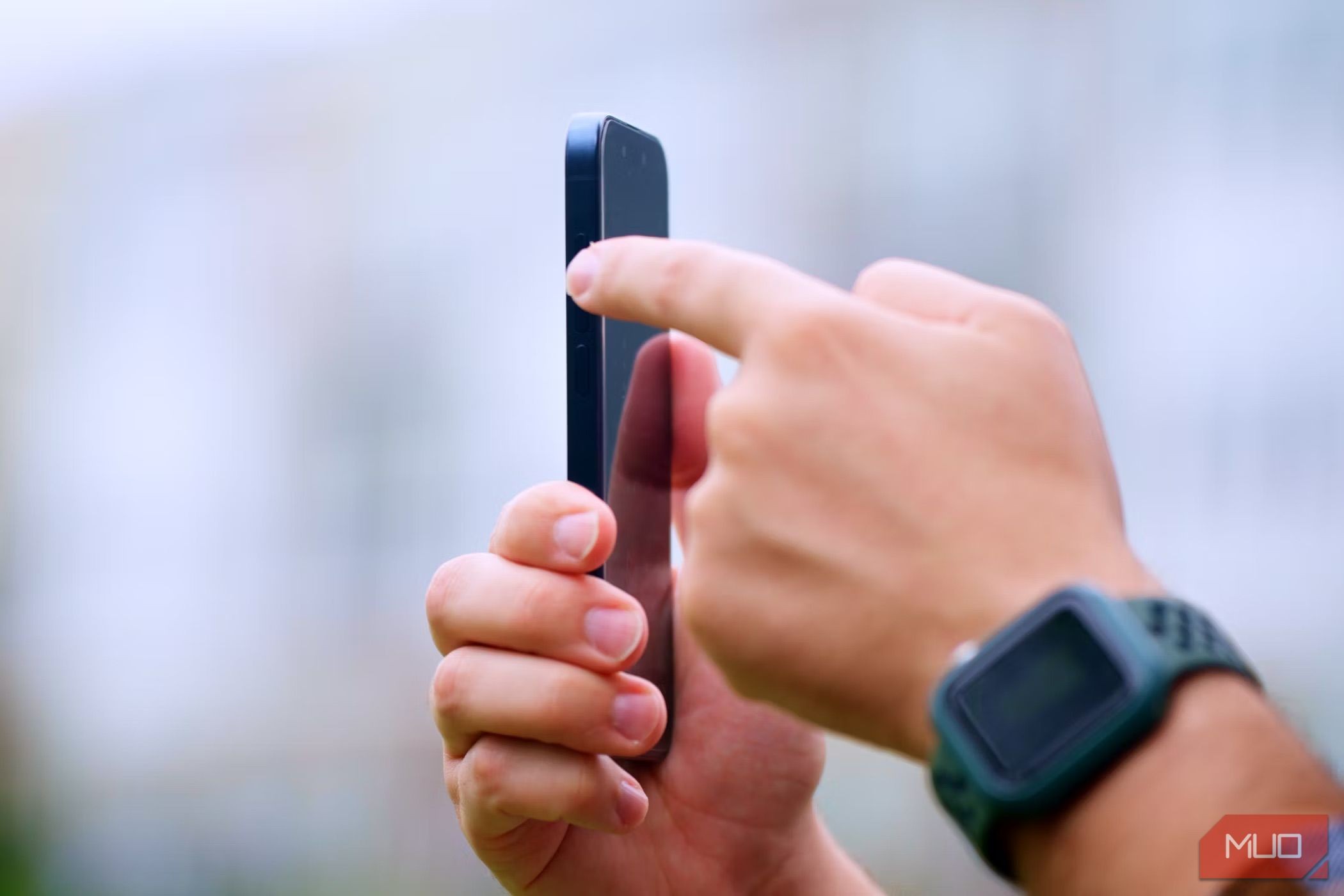 iPhone 15 Pro với ngón tay trái bấm vào Action Button