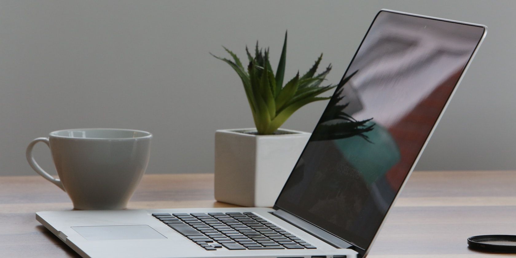 Laptop màu bạc và cốc trắng trên bàn