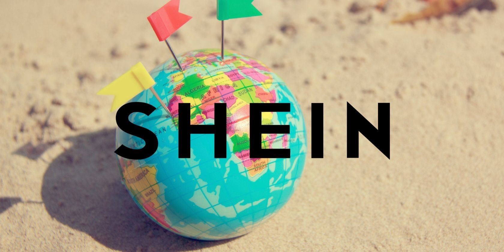 Logo Shein trước một quả cầu nhỏ trên cát