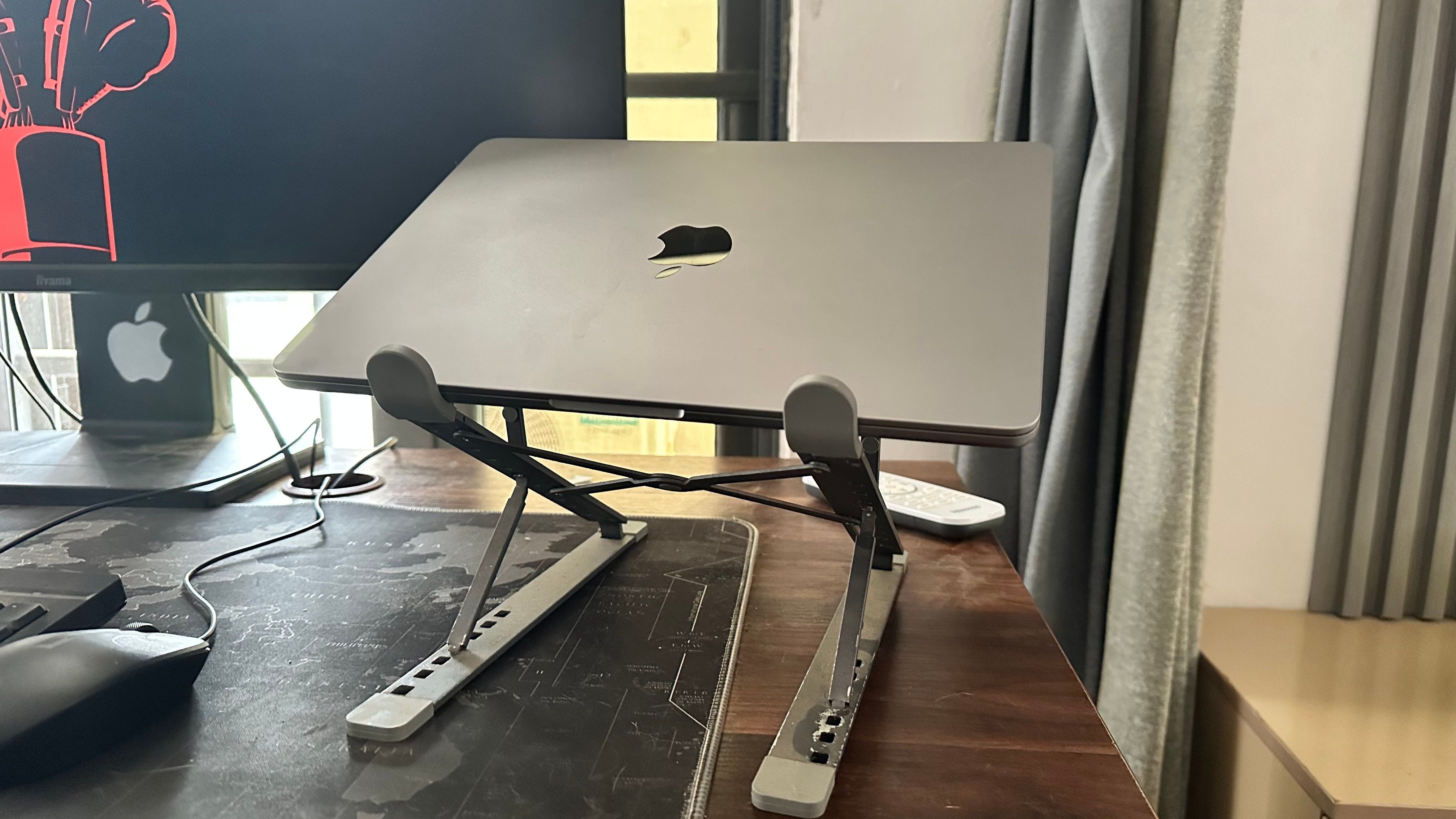 MacBook trên giá đỡ laptop bên cạnh màn hình