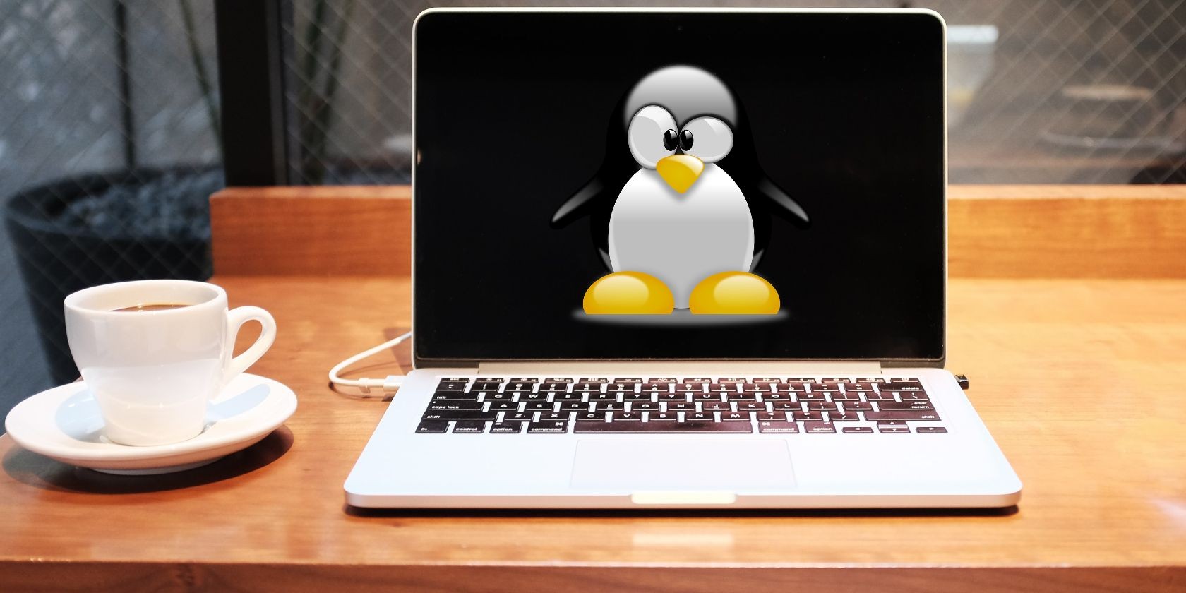 Màn hình laptop với logo Linux và một tách trà bên cạnh