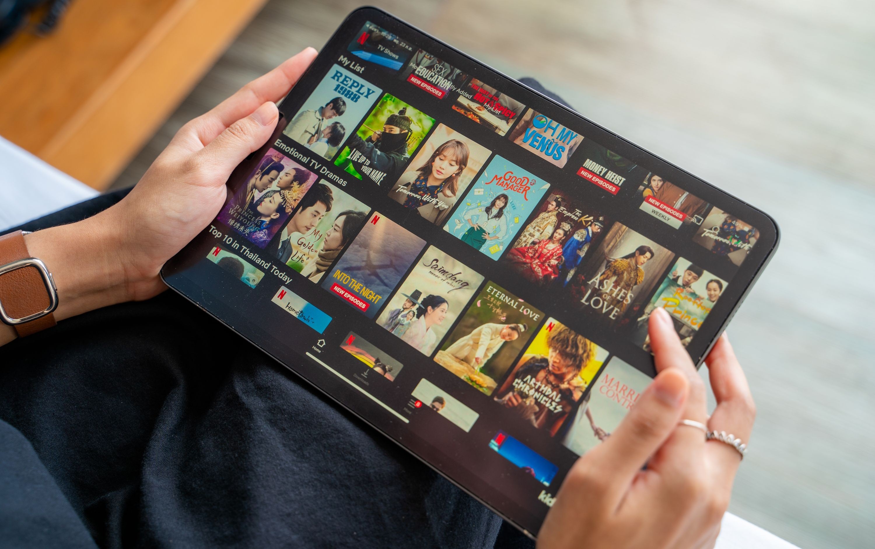 Một người phụ nữ cầm iPad đang duyệt thư viện Netflix
