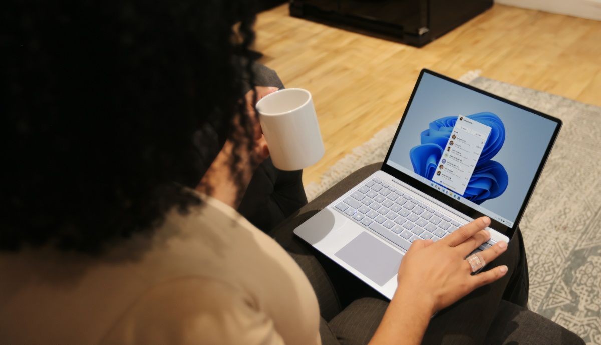 Một phụ nữ sử dụng máy tính Windows trong khi cầm cốc