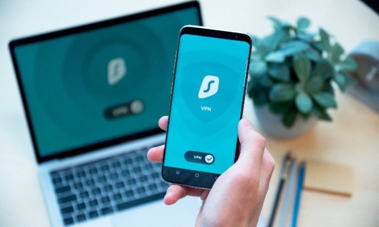 Người cầm điện thoại hiển thị kết nối VPN trên laptop cũng hiển thị kết nối VPN