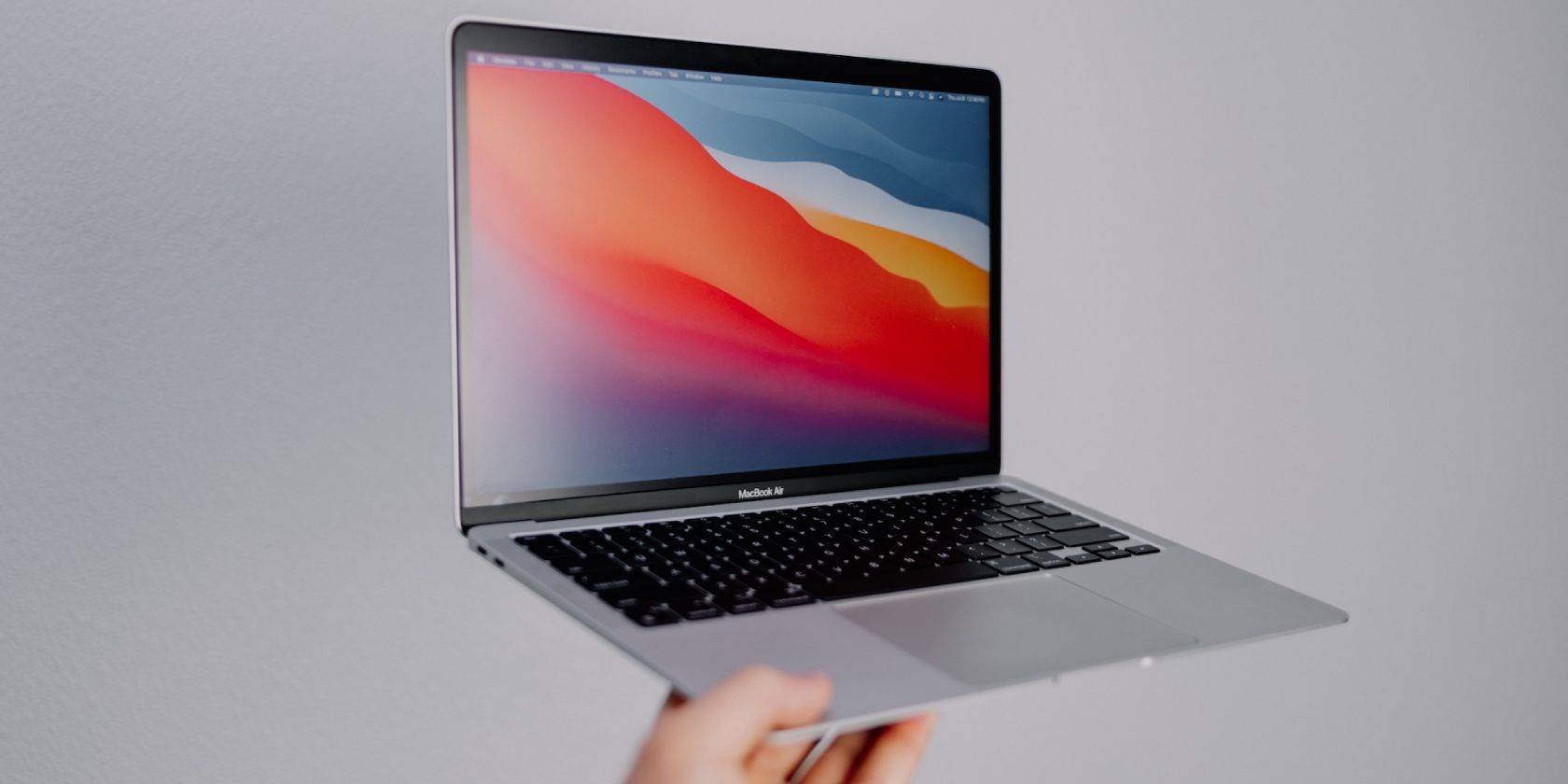 Người cầm MacBook Air trên nền xám