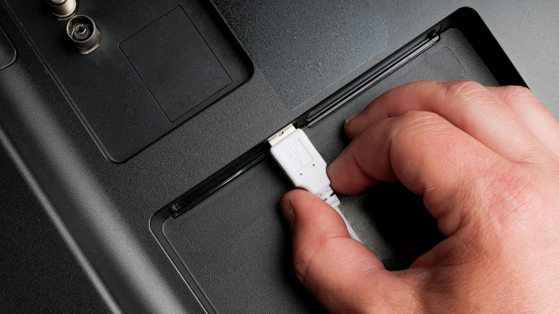 Người đàn ông cắm cáp USB loại A vào cổng sau của TV
