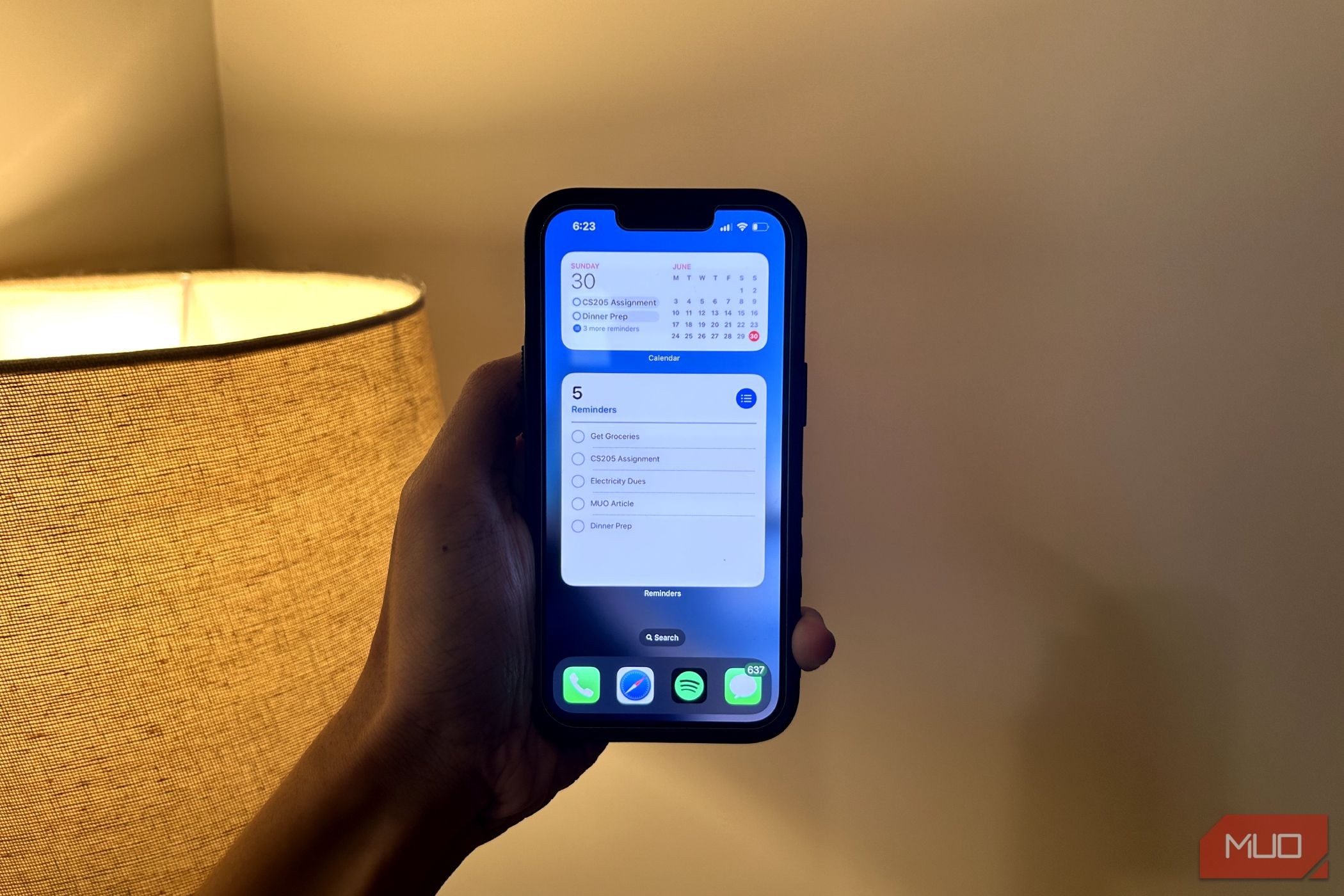 Người đàn ông cầm iPhone hiển thị widget Calendar và Reminders