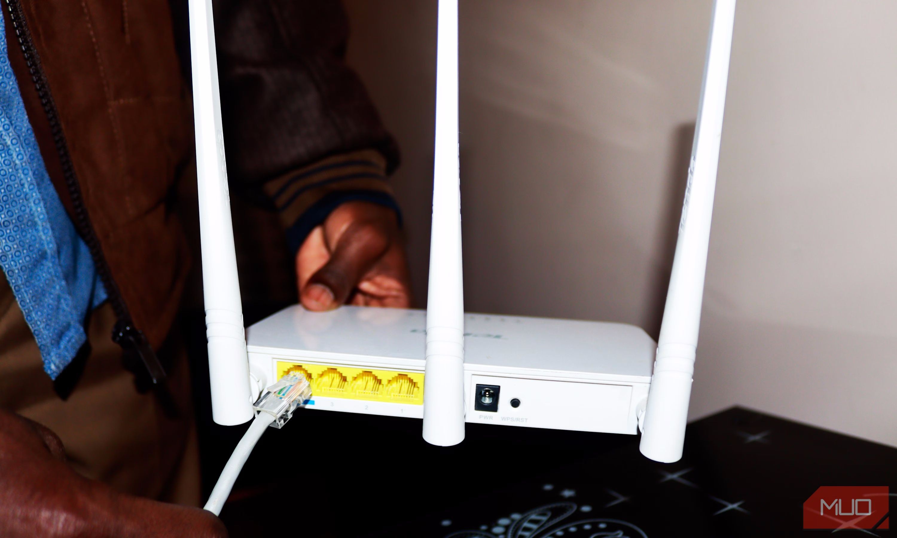 Người đàn ông cầm router Wi-Fi và cố gắng kết nối cáp Ethernet