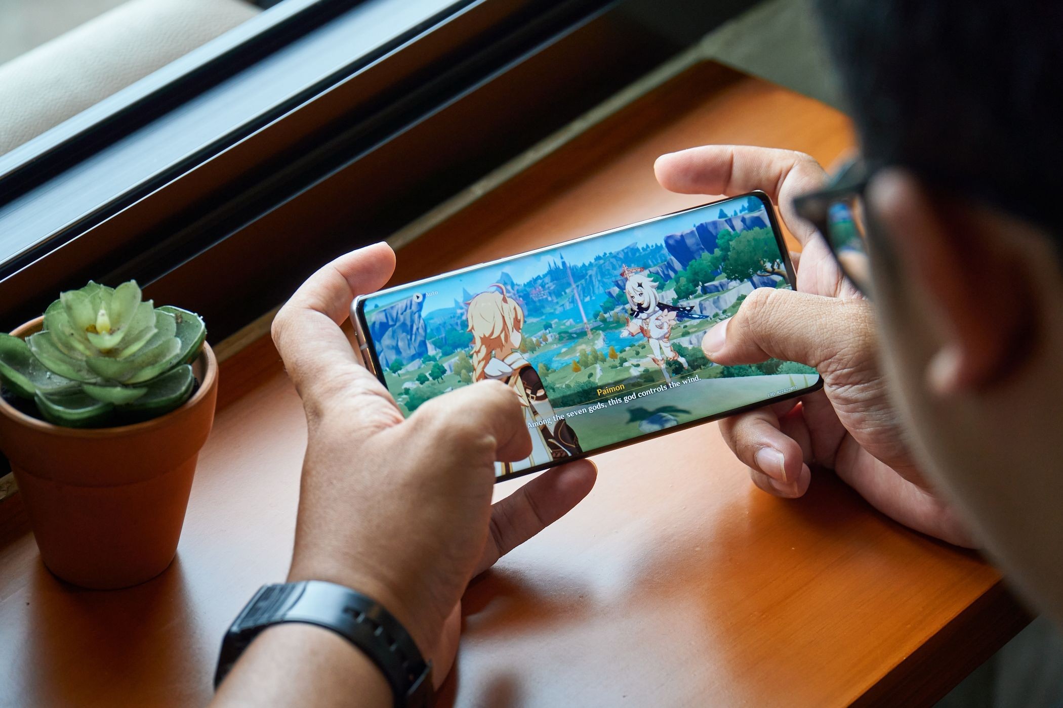 Người đàn ông chơi Genshin Impact trên điện thoại Android