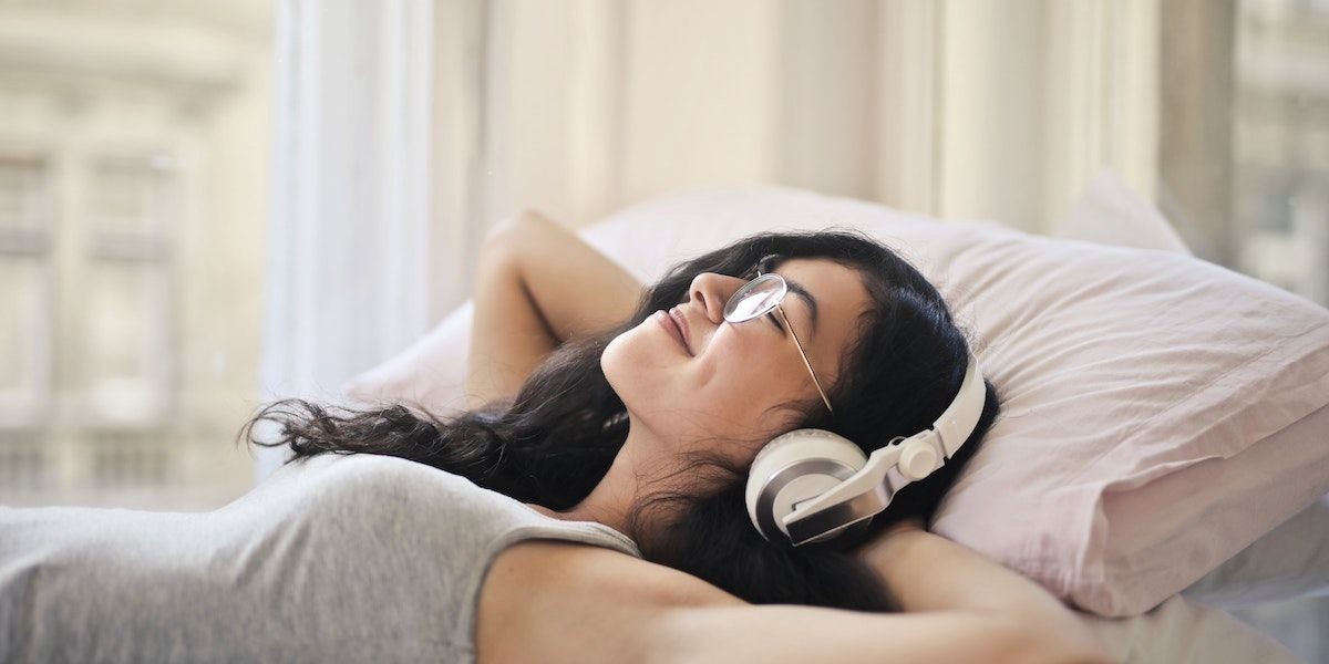 Người phụ nữ thư giãn trên giường với âm nhạc