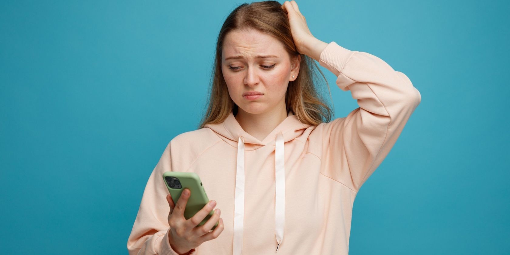 Người phụ nữ trẻ giữ tay lên đầu trong khi cầm và nhìn vào điện thoại di động