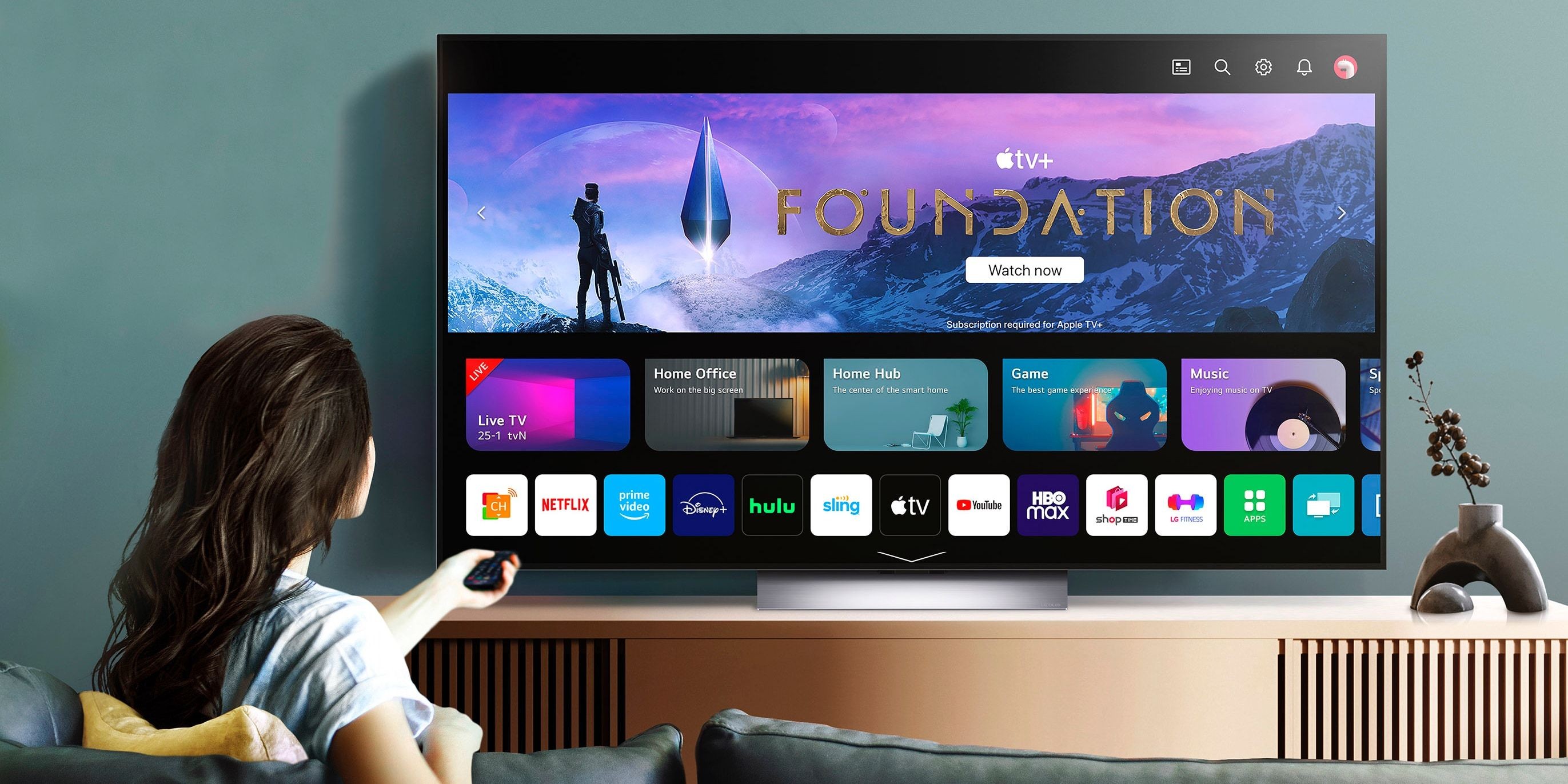 Người phụ nữ trên ghế sofa xem chương trình Foundation trên LG