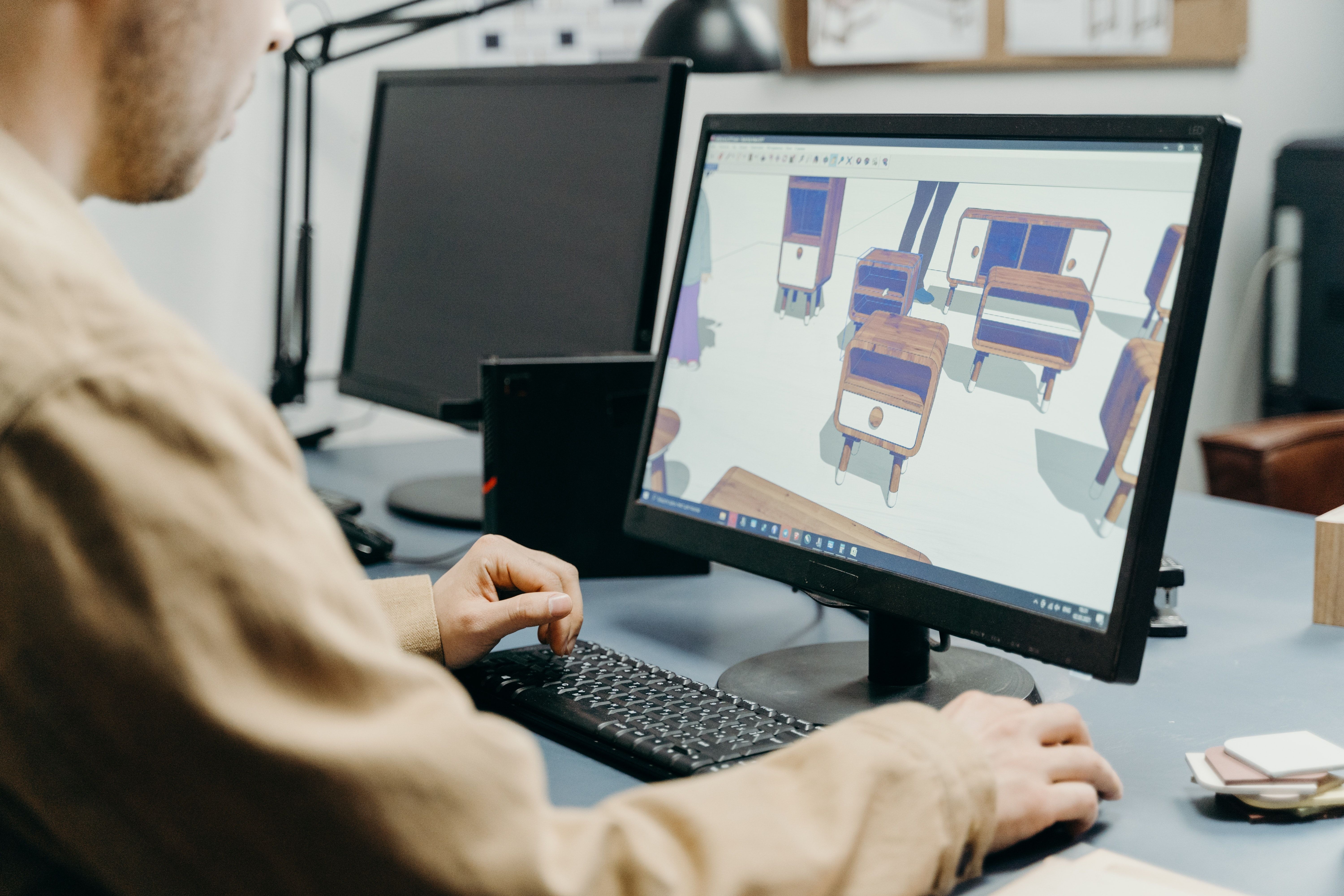 Nhà thiết kế nam đối diện với máy tính, làm việc trên mô hình đồ nội thất 3D