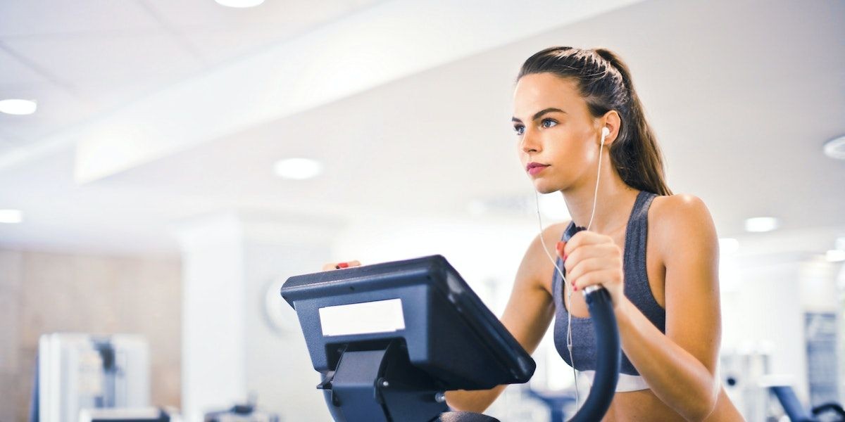 Nữ vận động viên trẻ tập luyện một mình trên máy chạy bộ trong phòng tập hiện đại