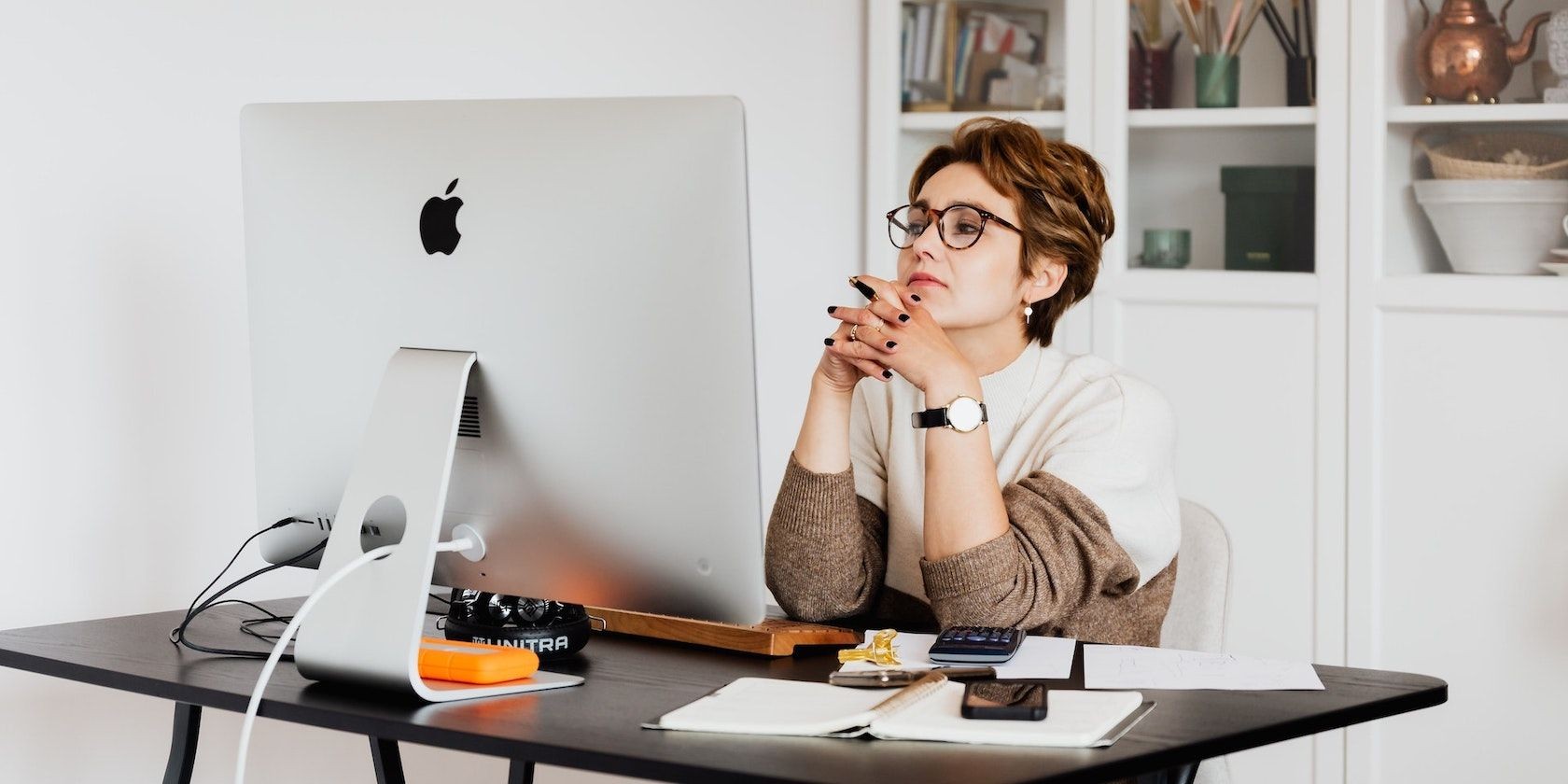 Phụ nữ đeo kính suy nghĩ khi sử dụng iMac