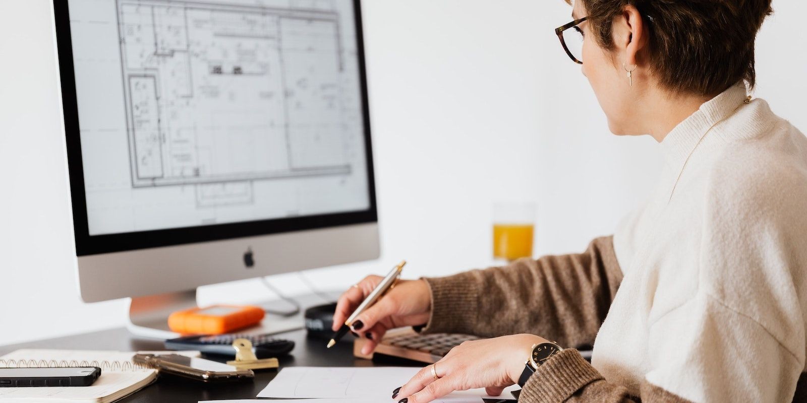 Phụ nữ đeo kính viết trên sổ tay khi sử dụng iMac