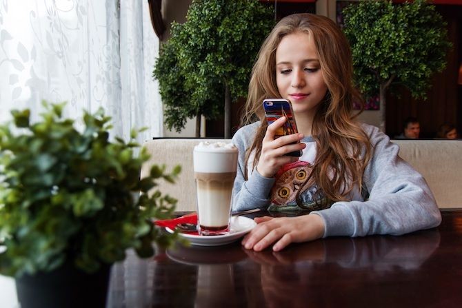 Phụ nữ sử dụng smartphone tại bàn cà phê