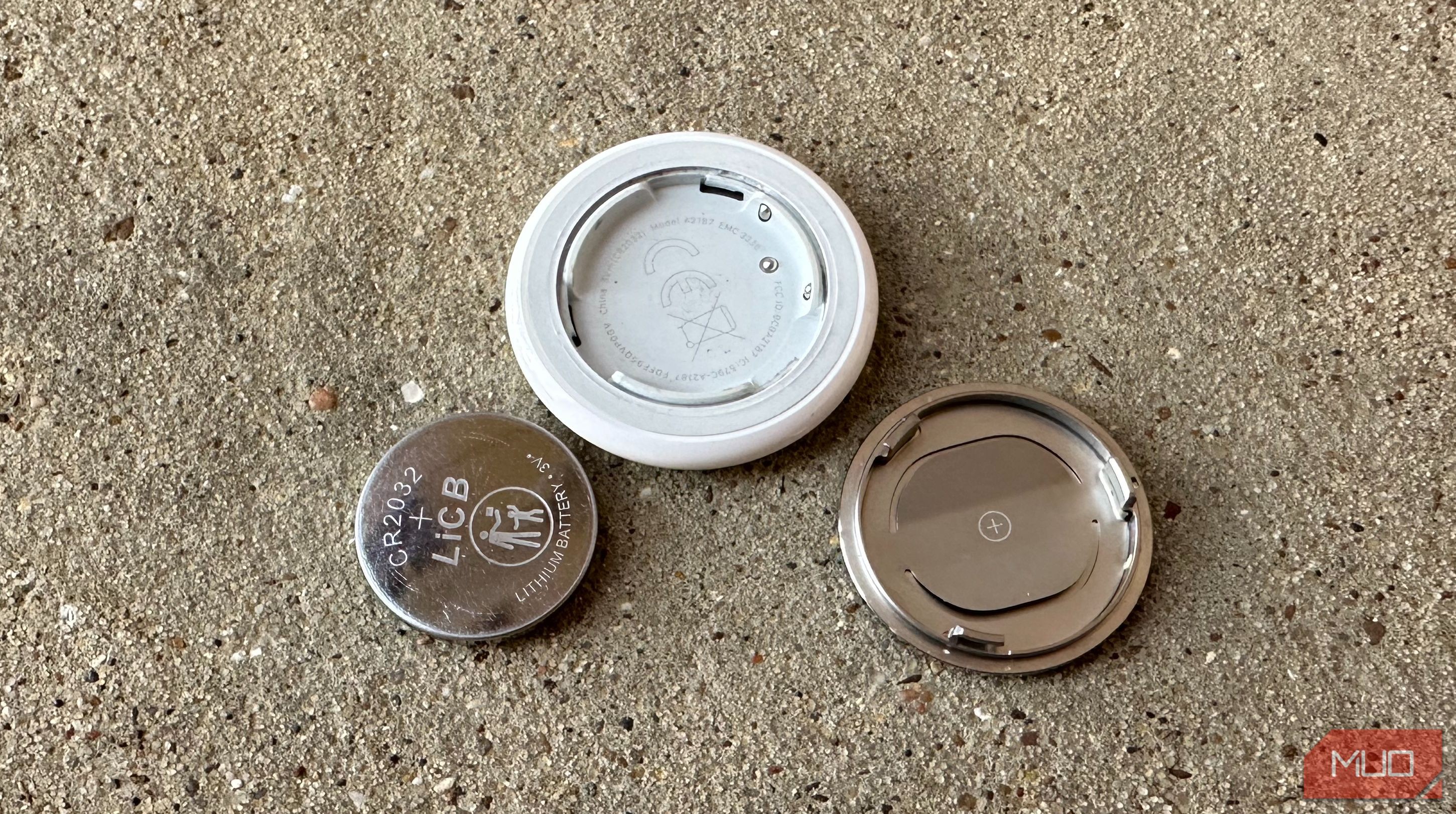 Pin và vỏ AirTag trên bề mặt thô