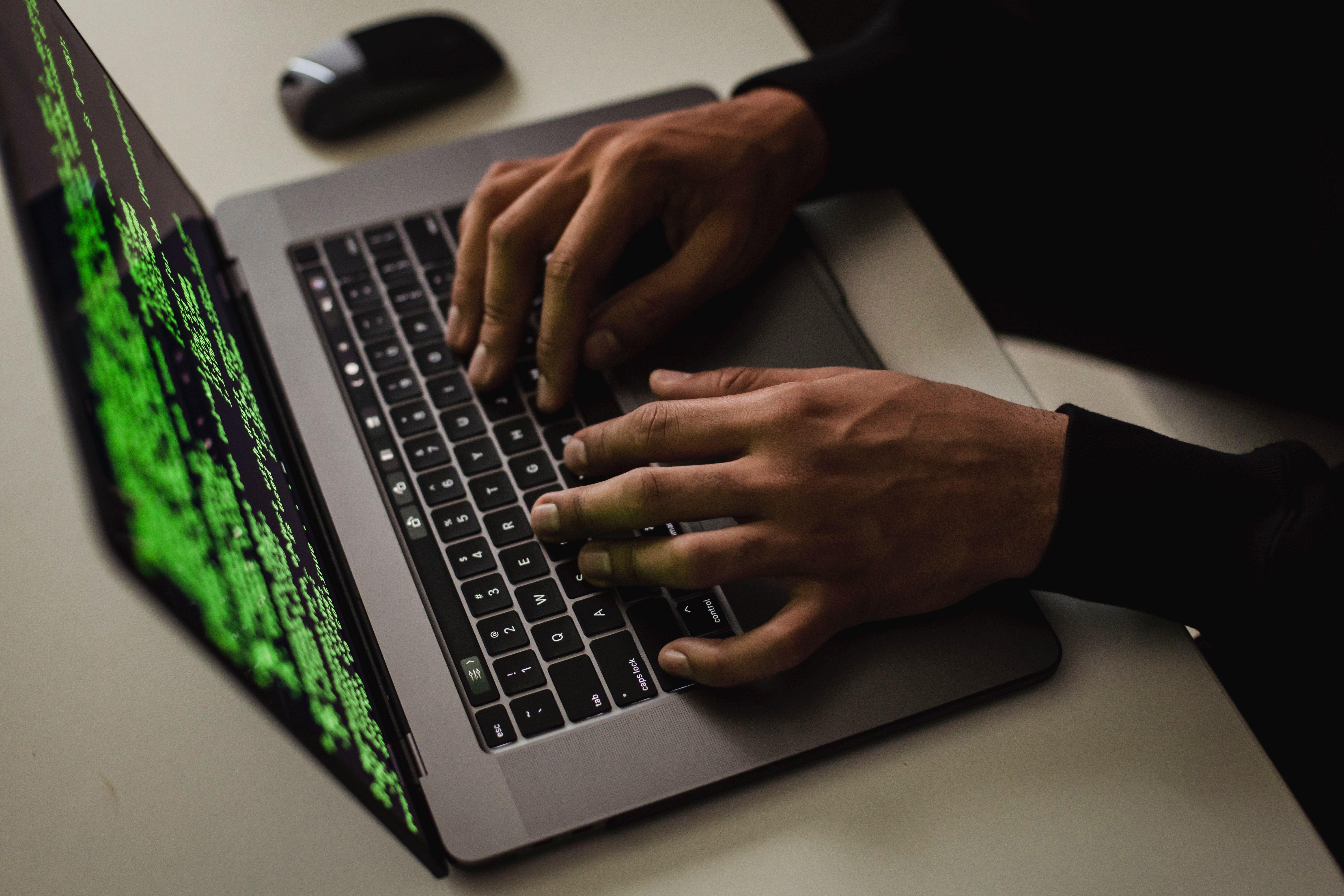 Tay đặt trên laptop với màn hình hiển thị mã