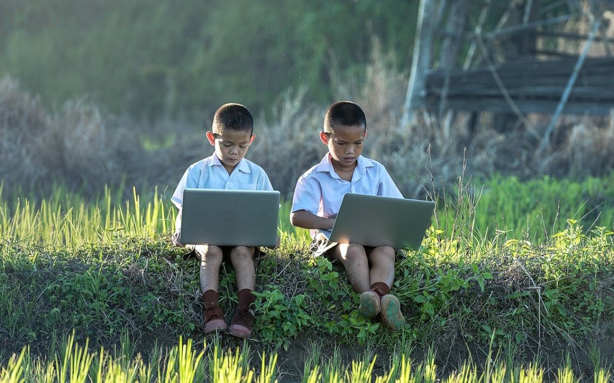 Trẻ em với laptop ngồi trên cỏ